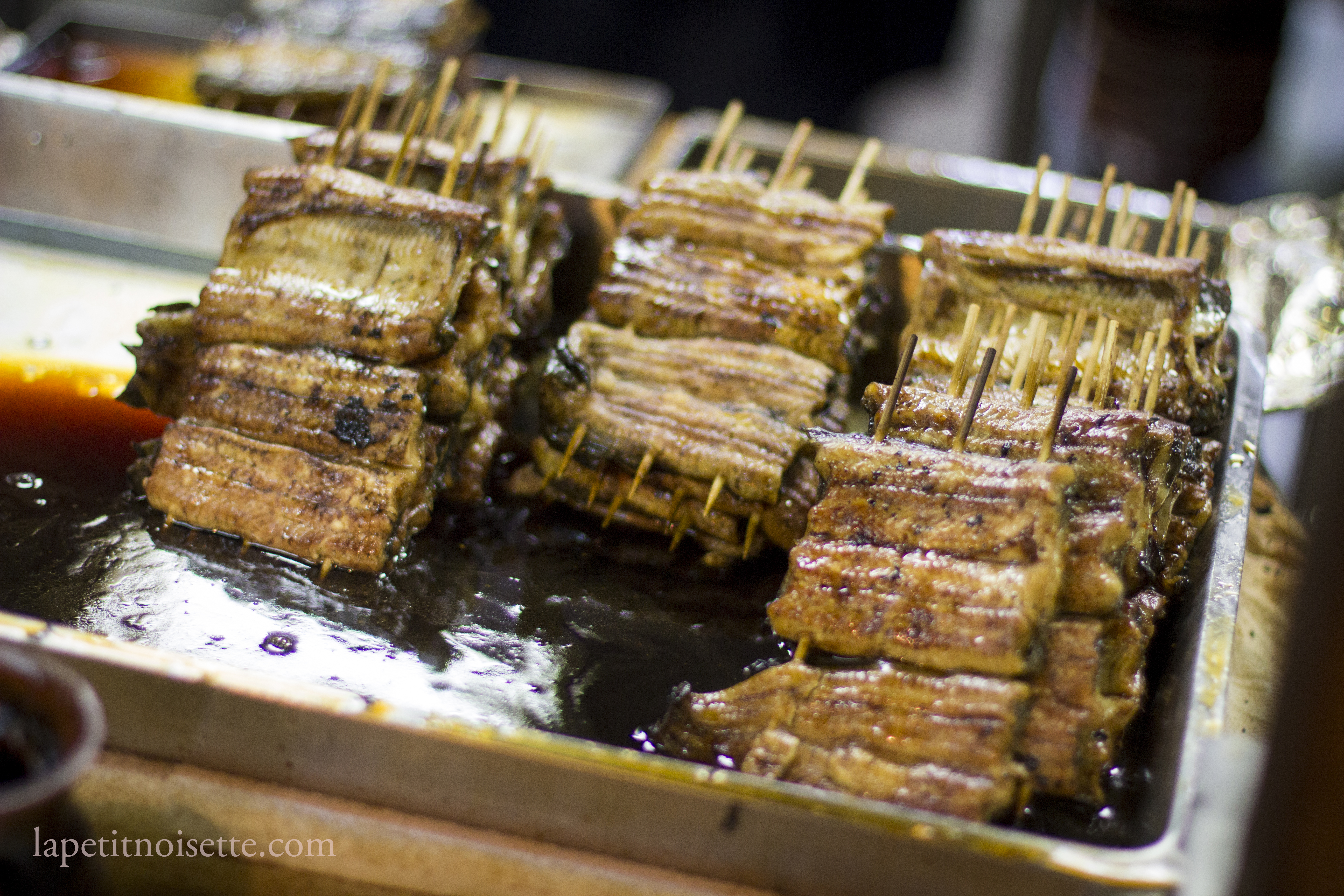 skewers of grilled eel soaking in sauce.