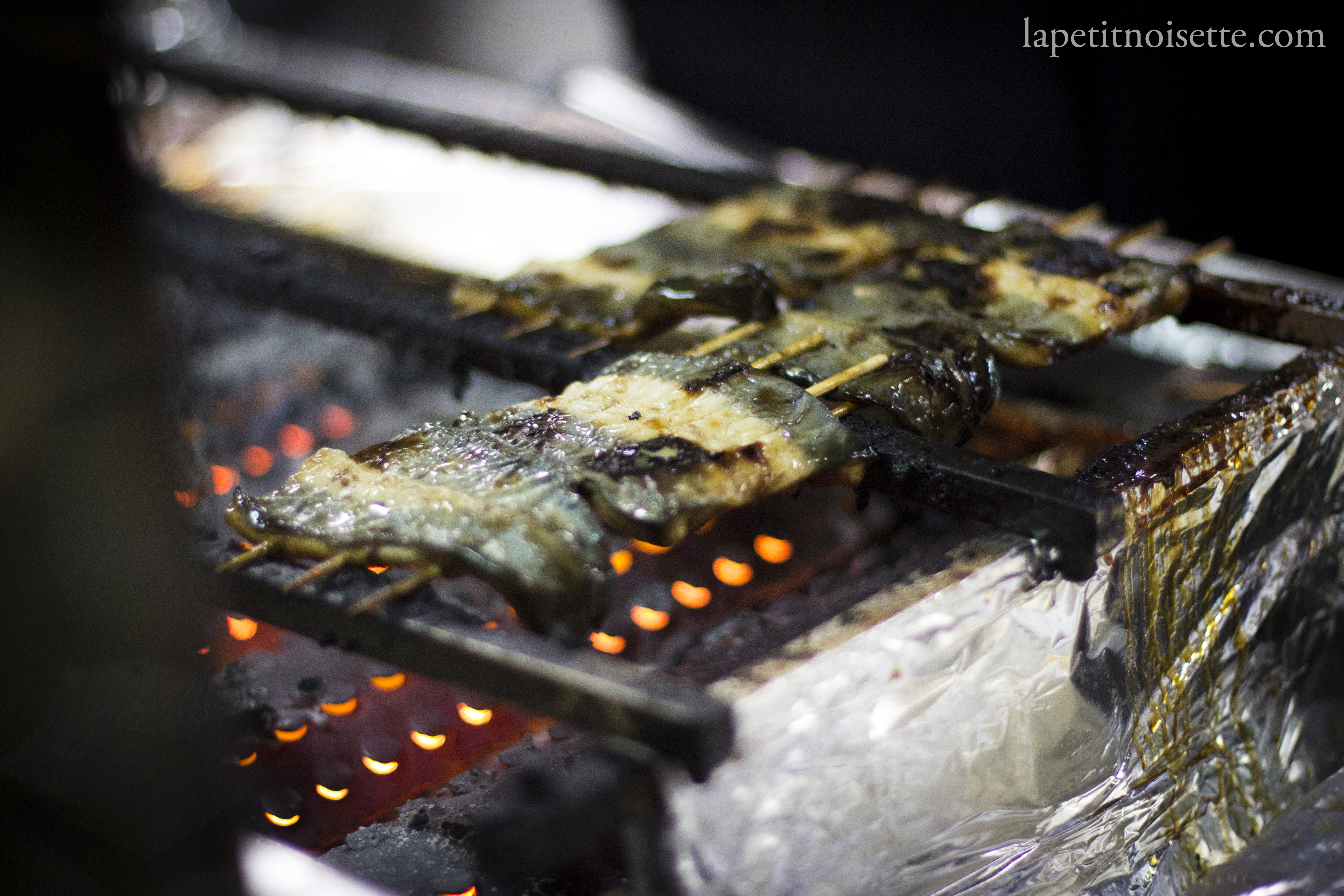 Skewers of eels being grilled over hot charcoal.
