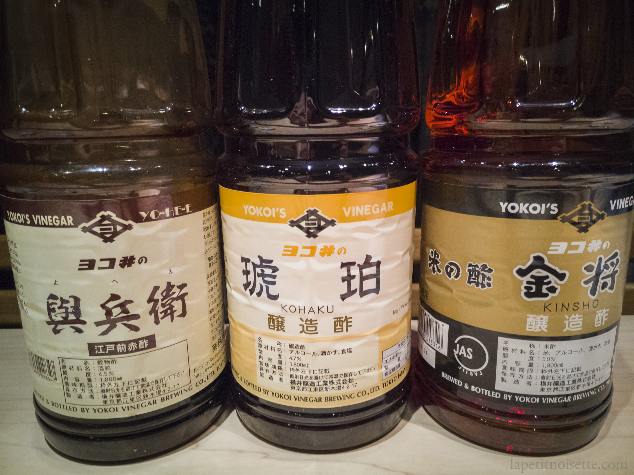 Yokoi's various grades of vinegars. From left to right: 與兵衛 赤酢 (よへえ/Yohee Akazu), 琥珀 赤酢（こはく/Kohaku Akazu), 金将 米の酢 (きんしょ/Kinsho)