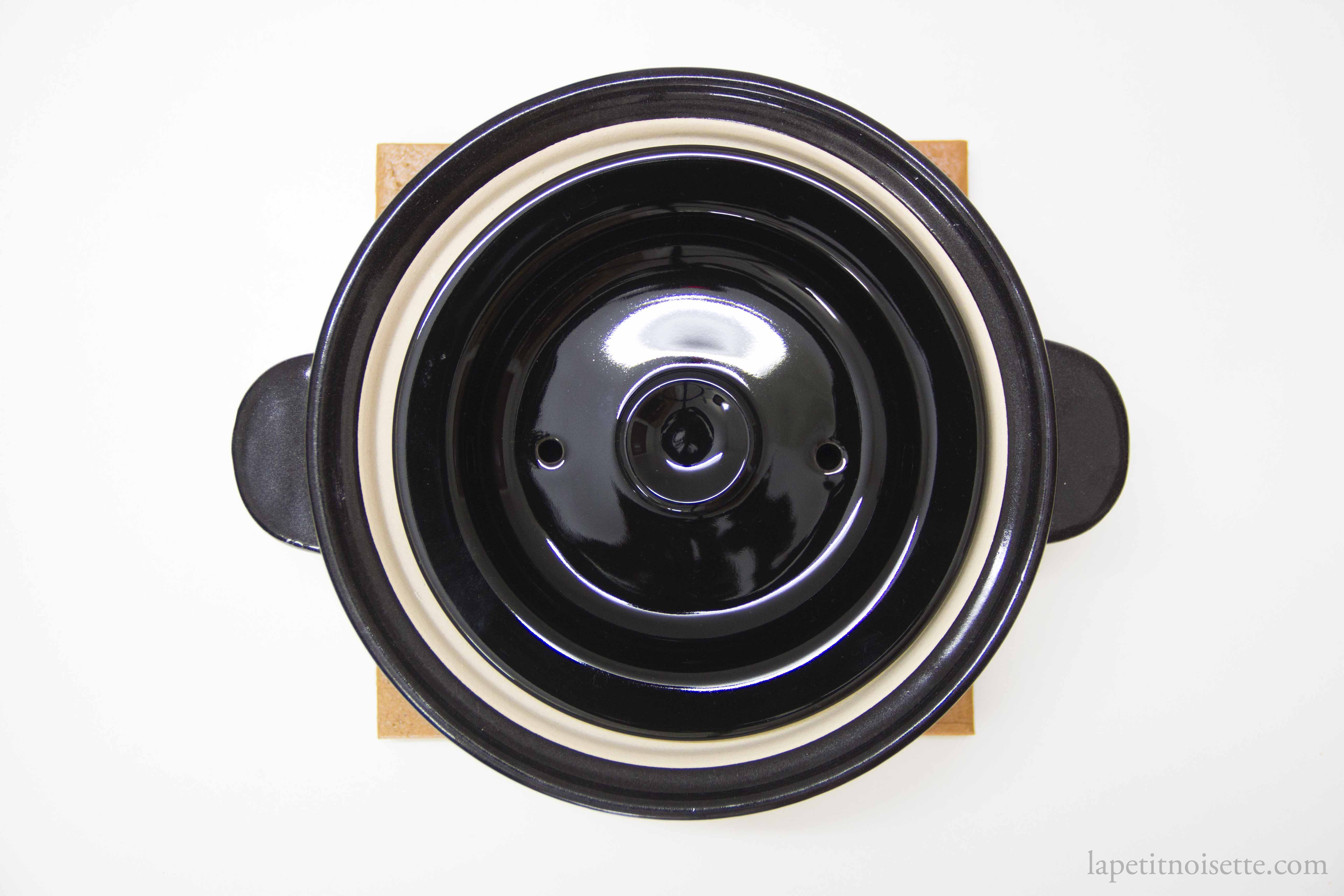 The inside of a traditional donabe rice cooker with and inner and outer lid.