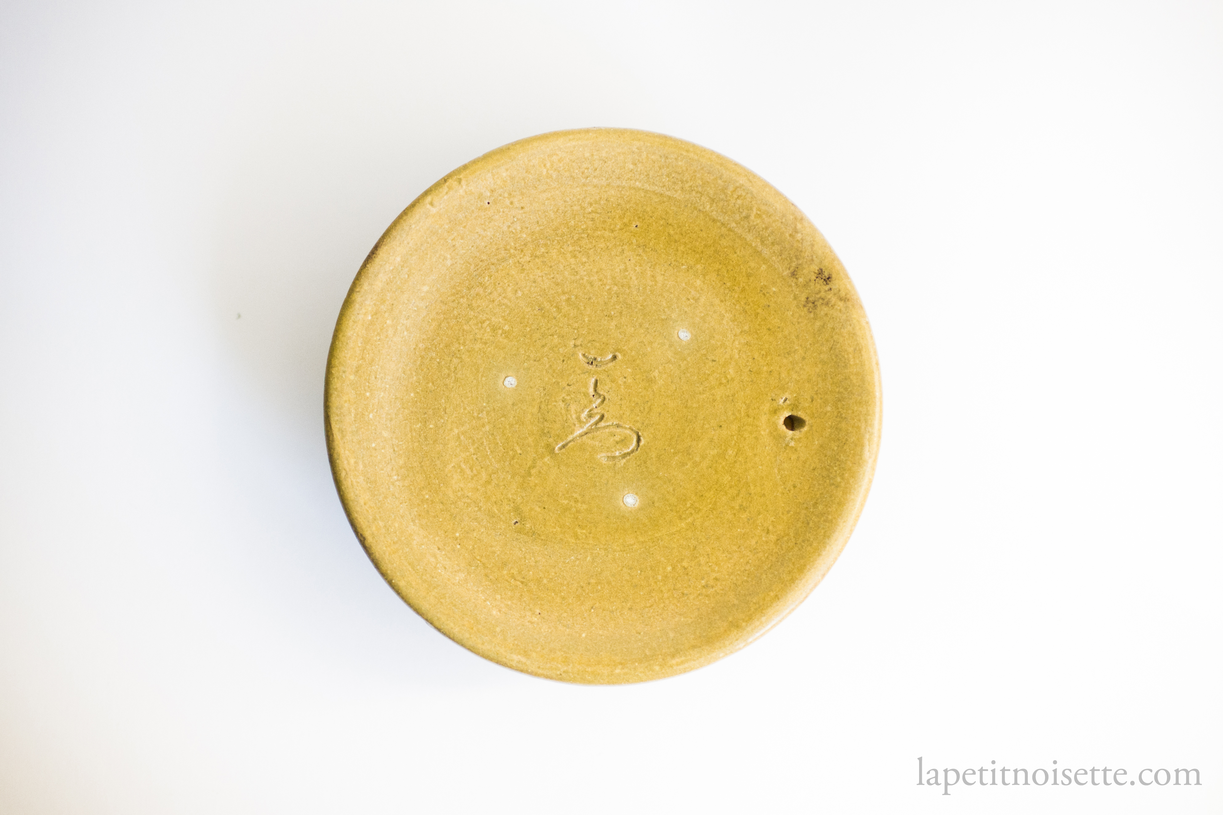 The underside of the lid of isshiro kiln's claypot rice cooker showing his signature.