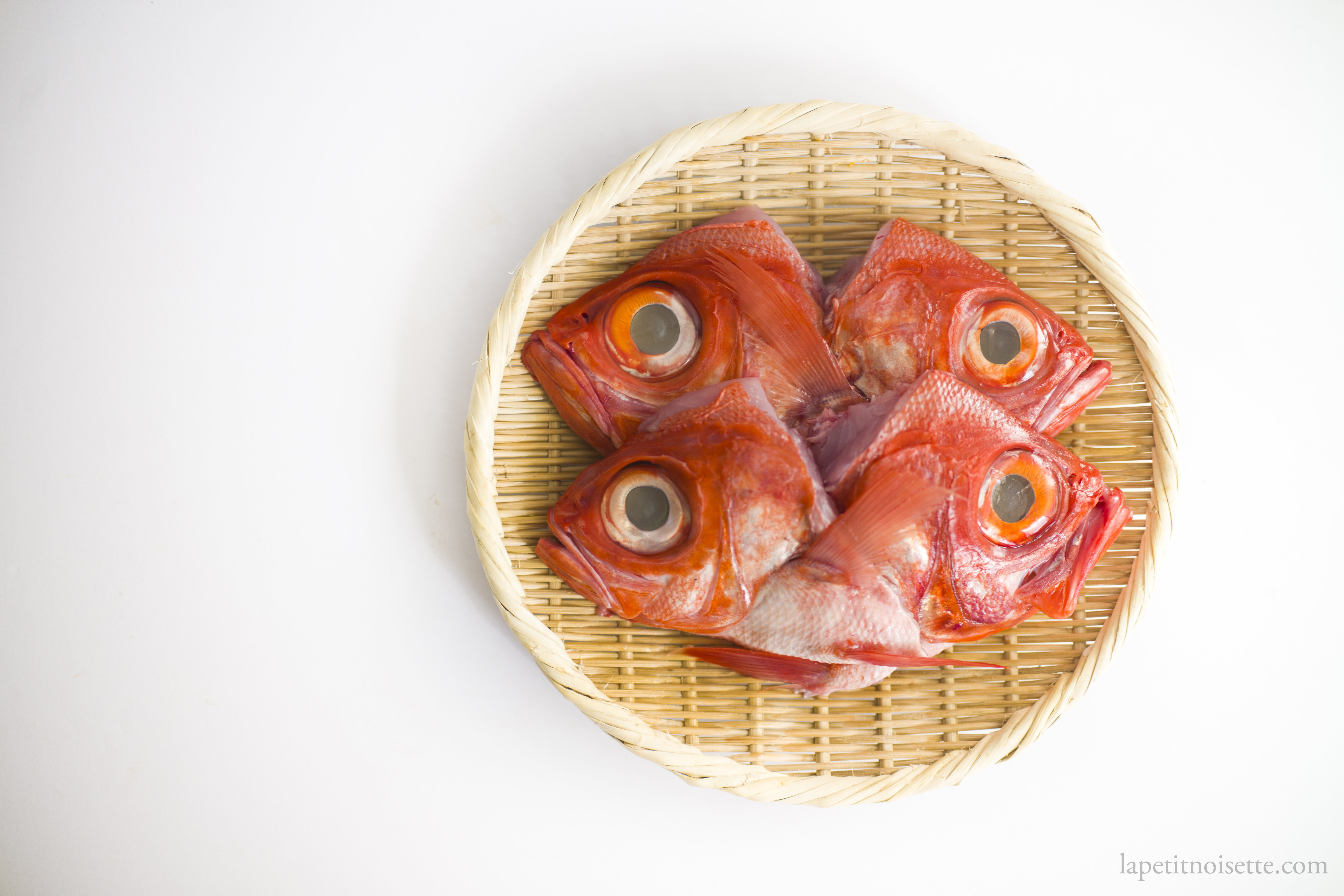 Kinmedai fish heads split in half and draining on a bamboo colander.
