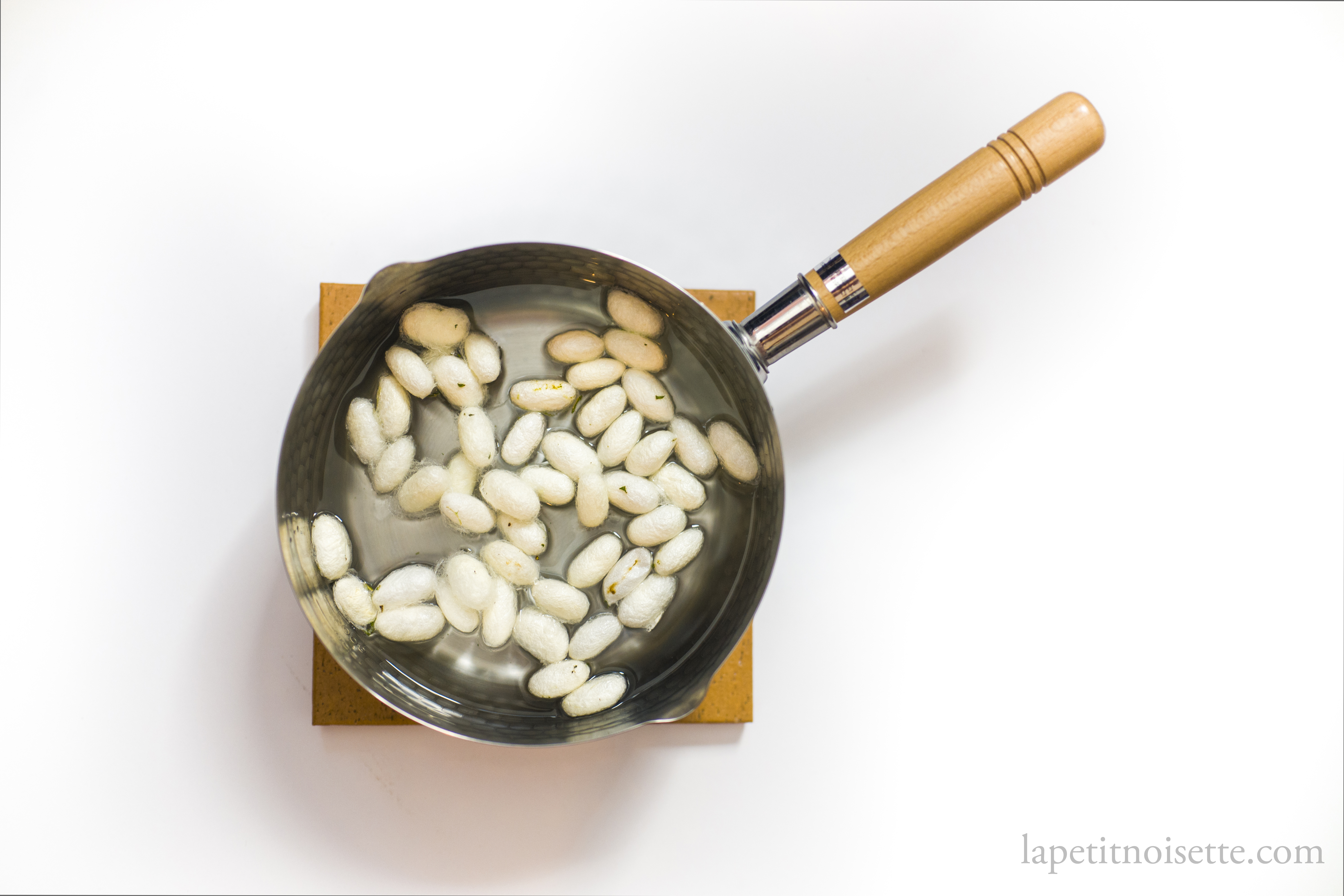 Boiling silkworm cocoons in water to kill the pupae.