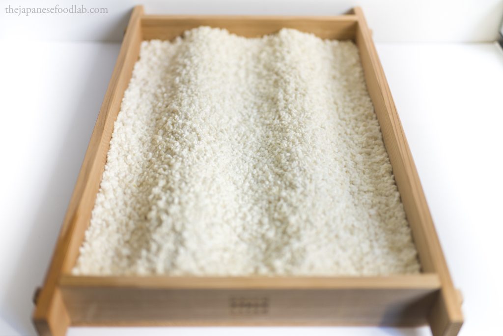 Freshly made rice koji grown on a wooden tray.