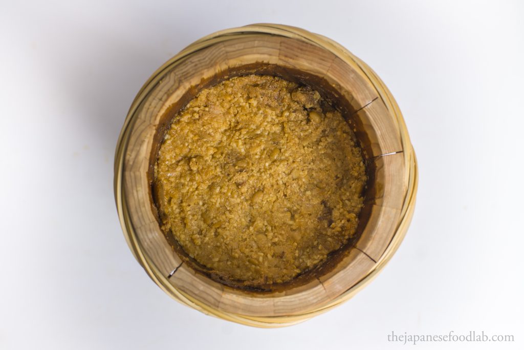 Traditional yellow miso packed and fermenting in a handmade wooden Japanese barrel.