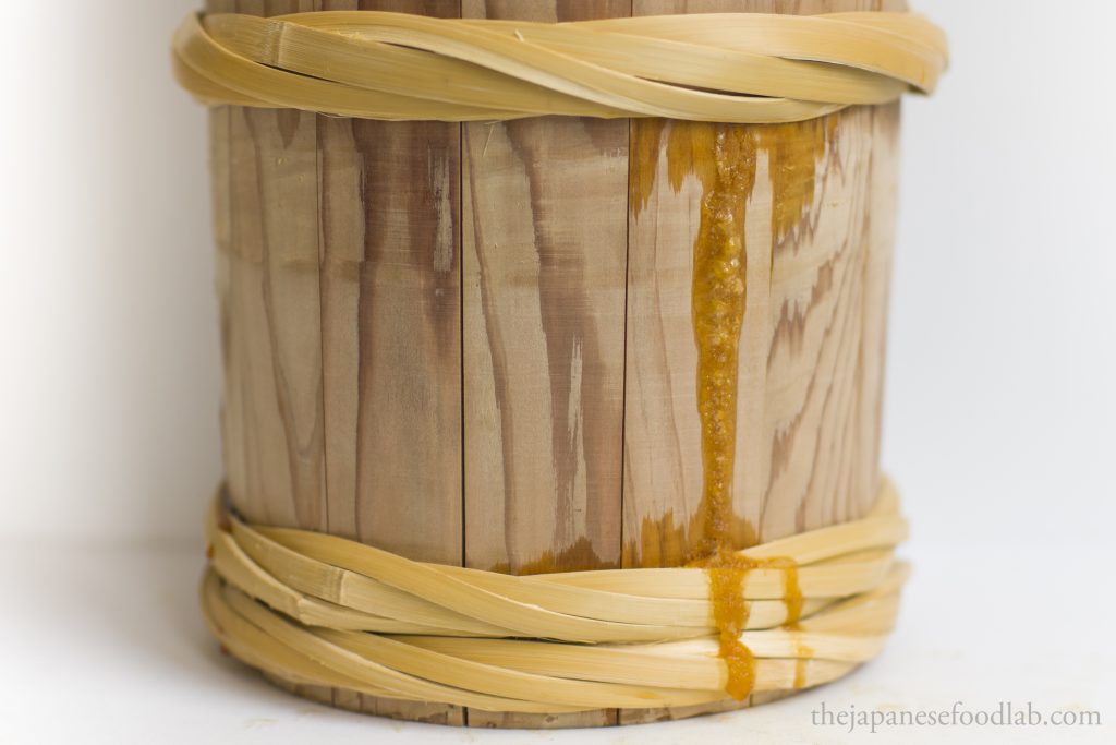 Yellow miso tamari leaking out of a wooden miso barrel.
