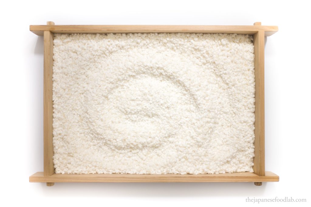 Freshly grown rice koji on a traditional Japanese wooden tray.